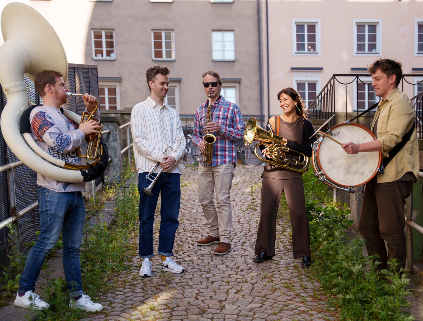 Grupp av 5 musikanter med olika blåsinstrument. 4 män och en kvinna.