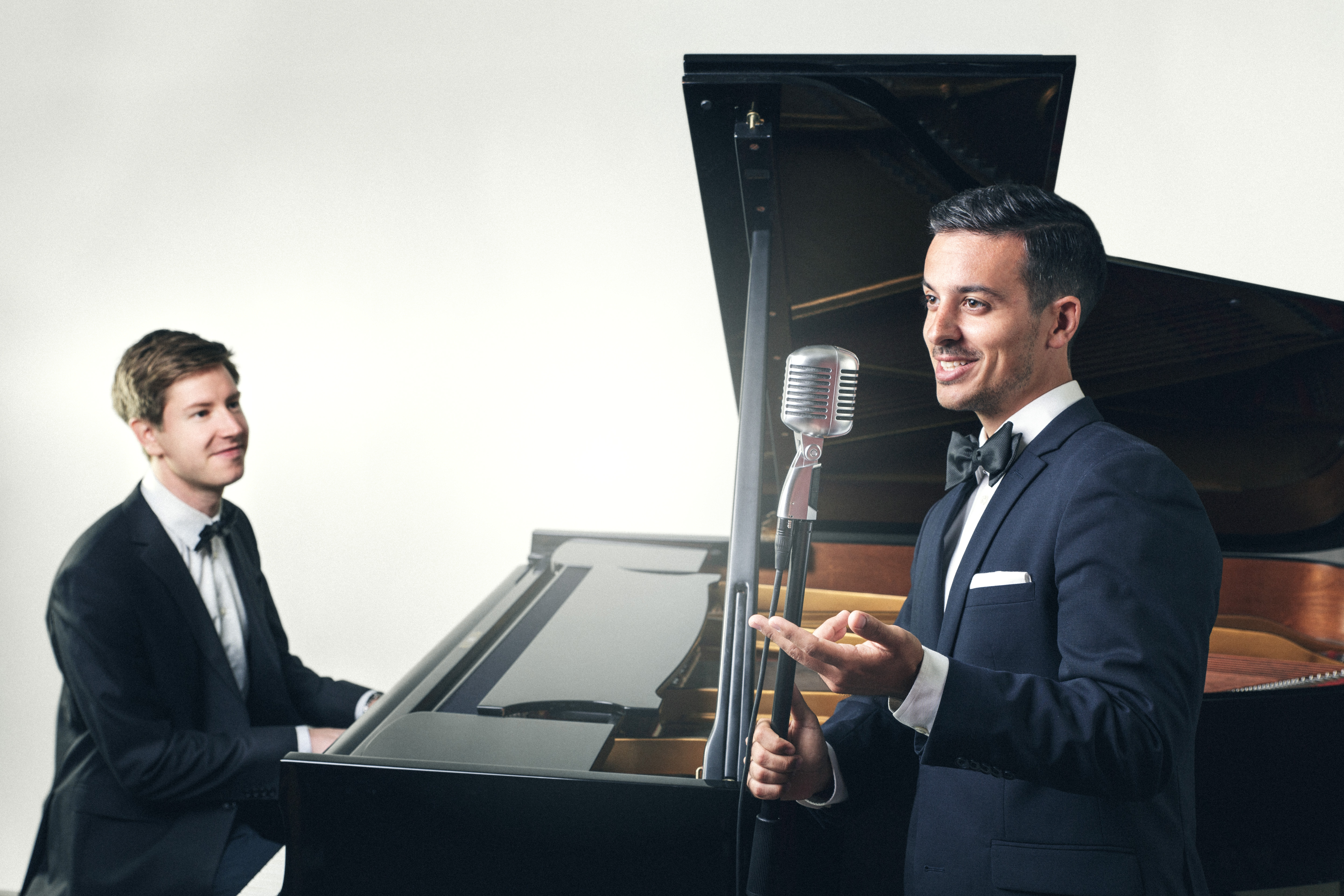 Två män. En spelar piano och den andra sjunger.