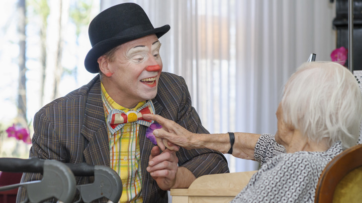 Clown pratar med sittande kvinna.